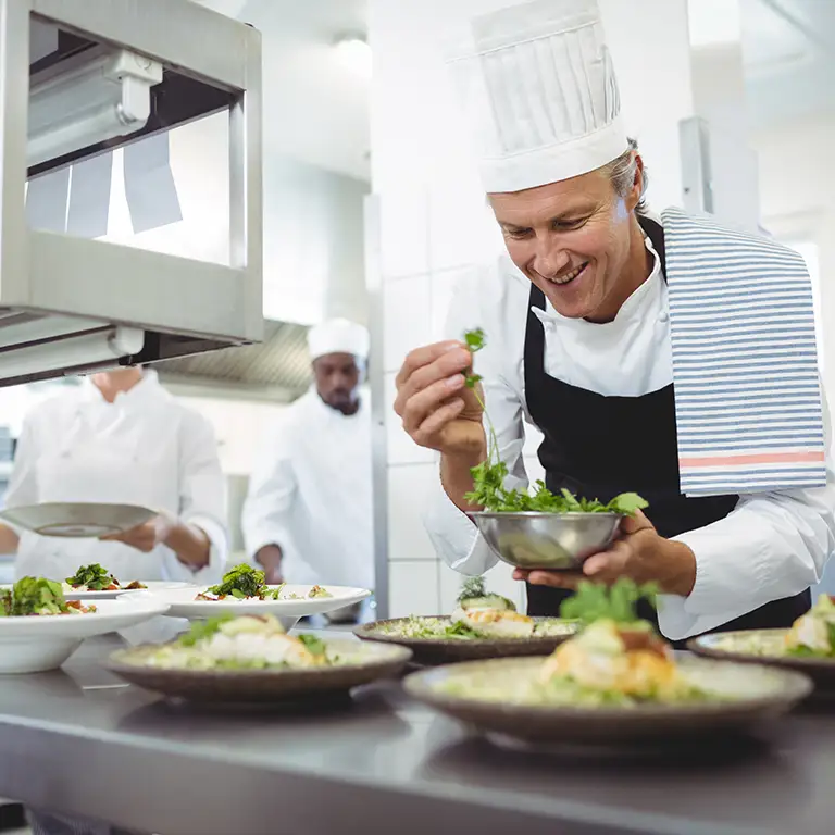 Happy chef preparing food representing restaurants and hospitality financial services.